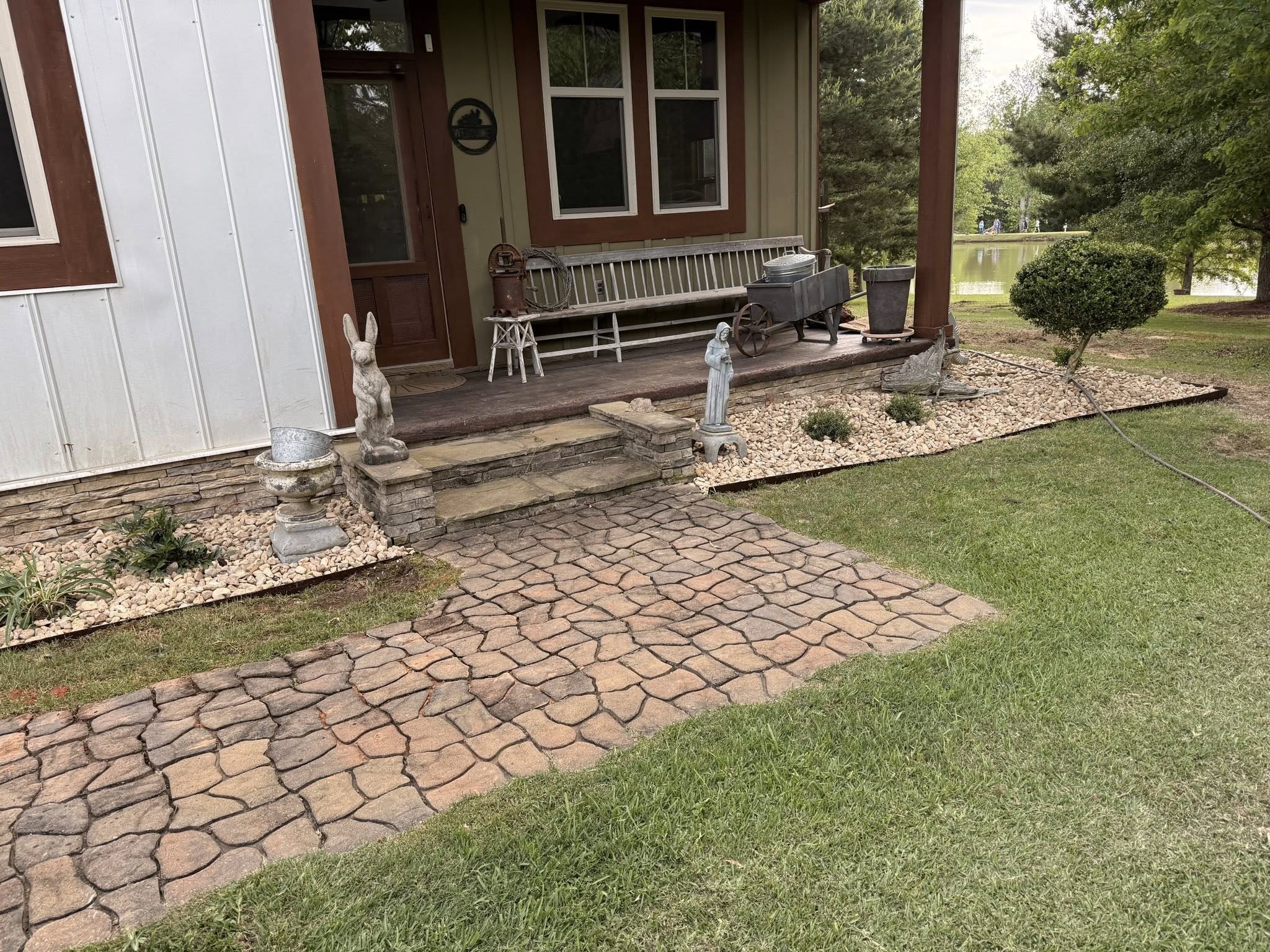 Finished entrance with stone walkway, river rock beds, and manicured landscaping