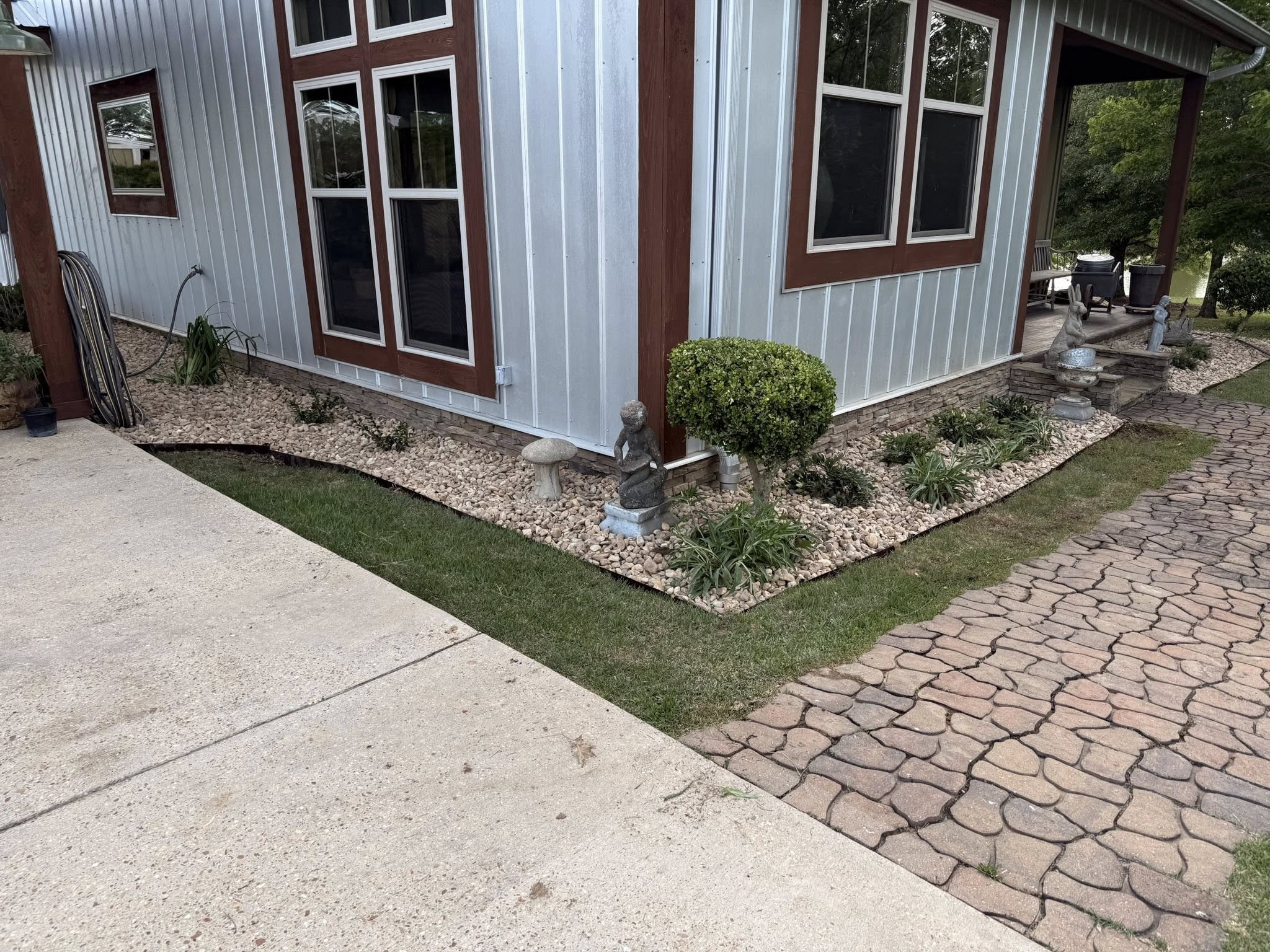 Completed landscaping with river rock beds, trimmed shrubs, and clean walkway
