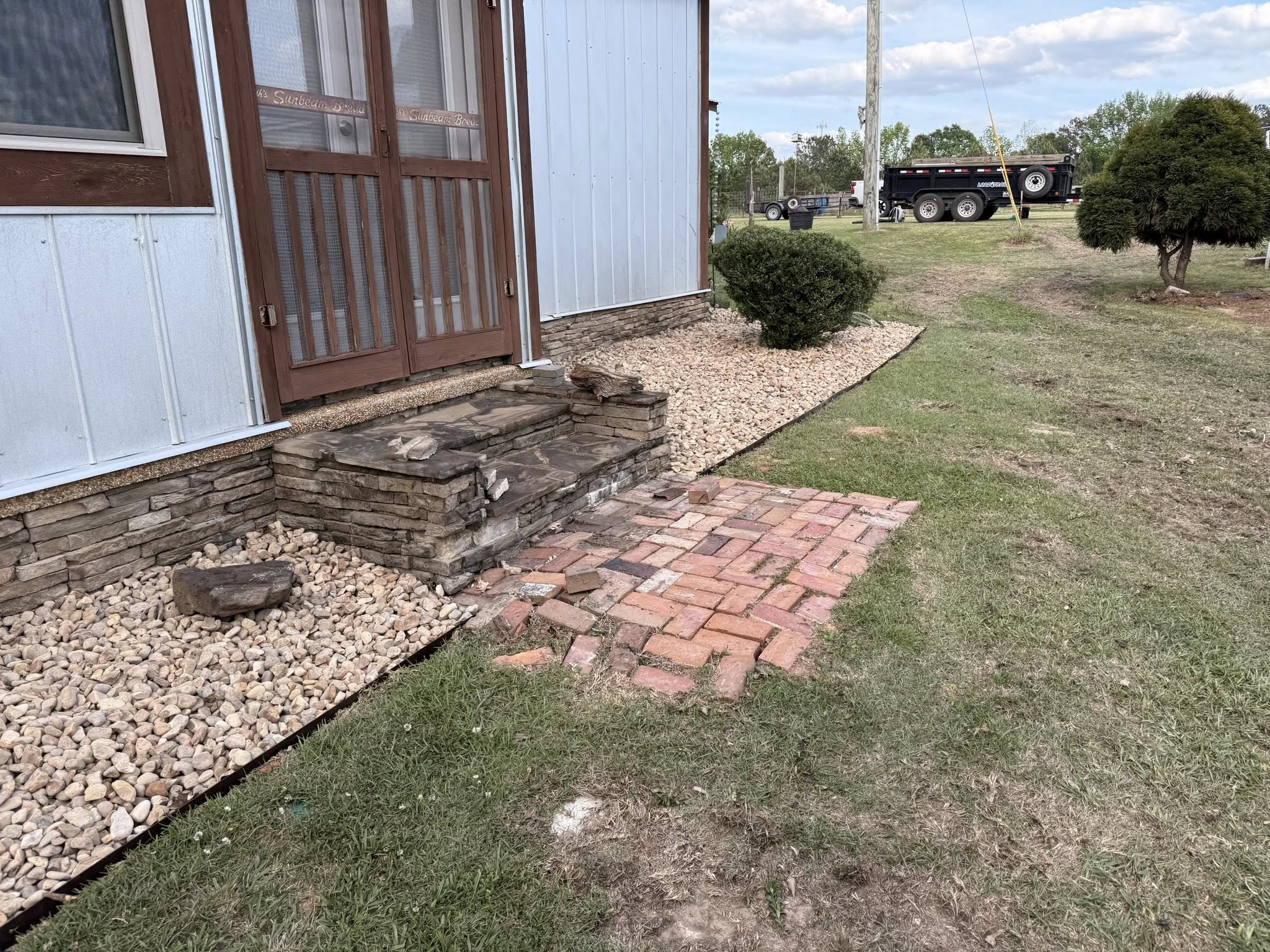 Property entrance area with basic brick walkway before professional landscaping